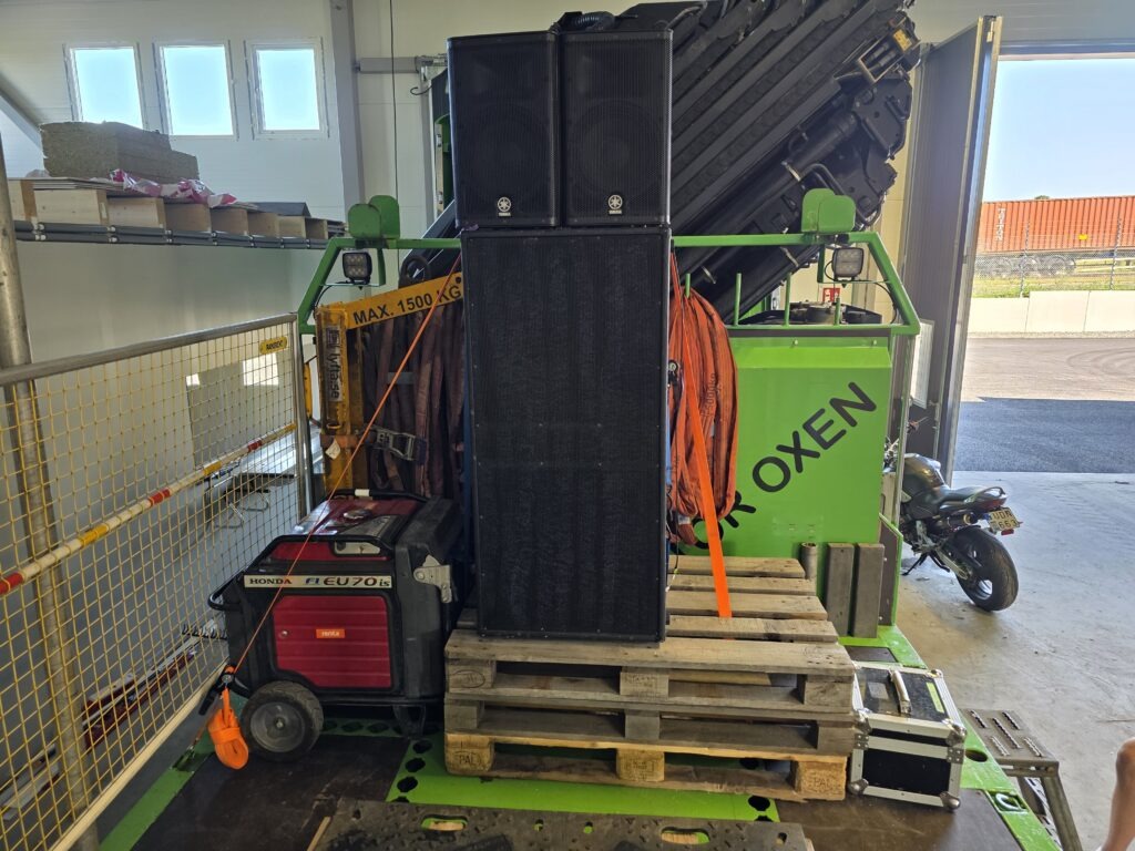 Professionell och säker montering av högtalare på kranbil med industriella spännband och elverk.