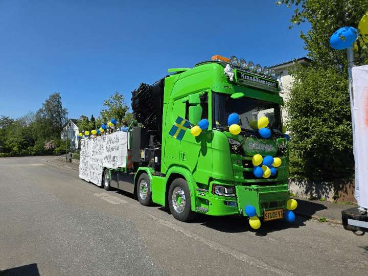 Studentflak i Västergötland med kraftfullt ljudsystem monterat på en grön kranbil i rullning.